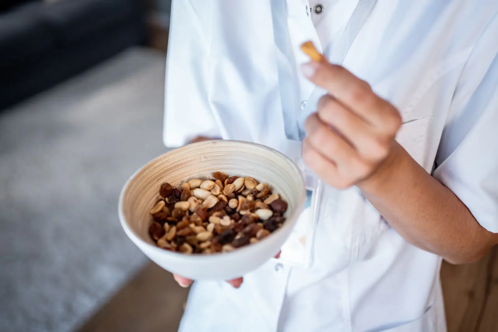 A person holding a bowl of mixed nuts.