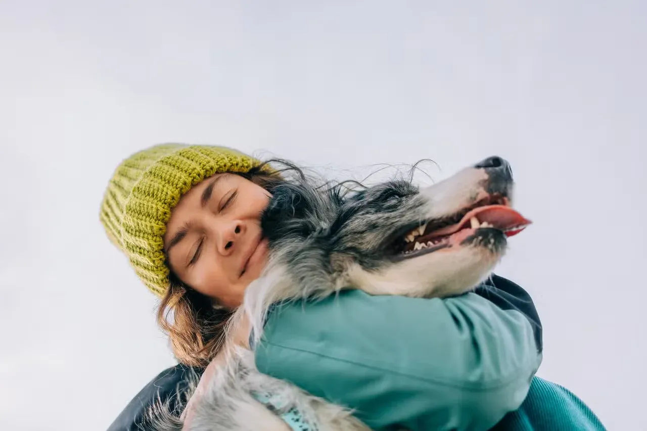 A dog owner being affectionate and showing love to her dog.