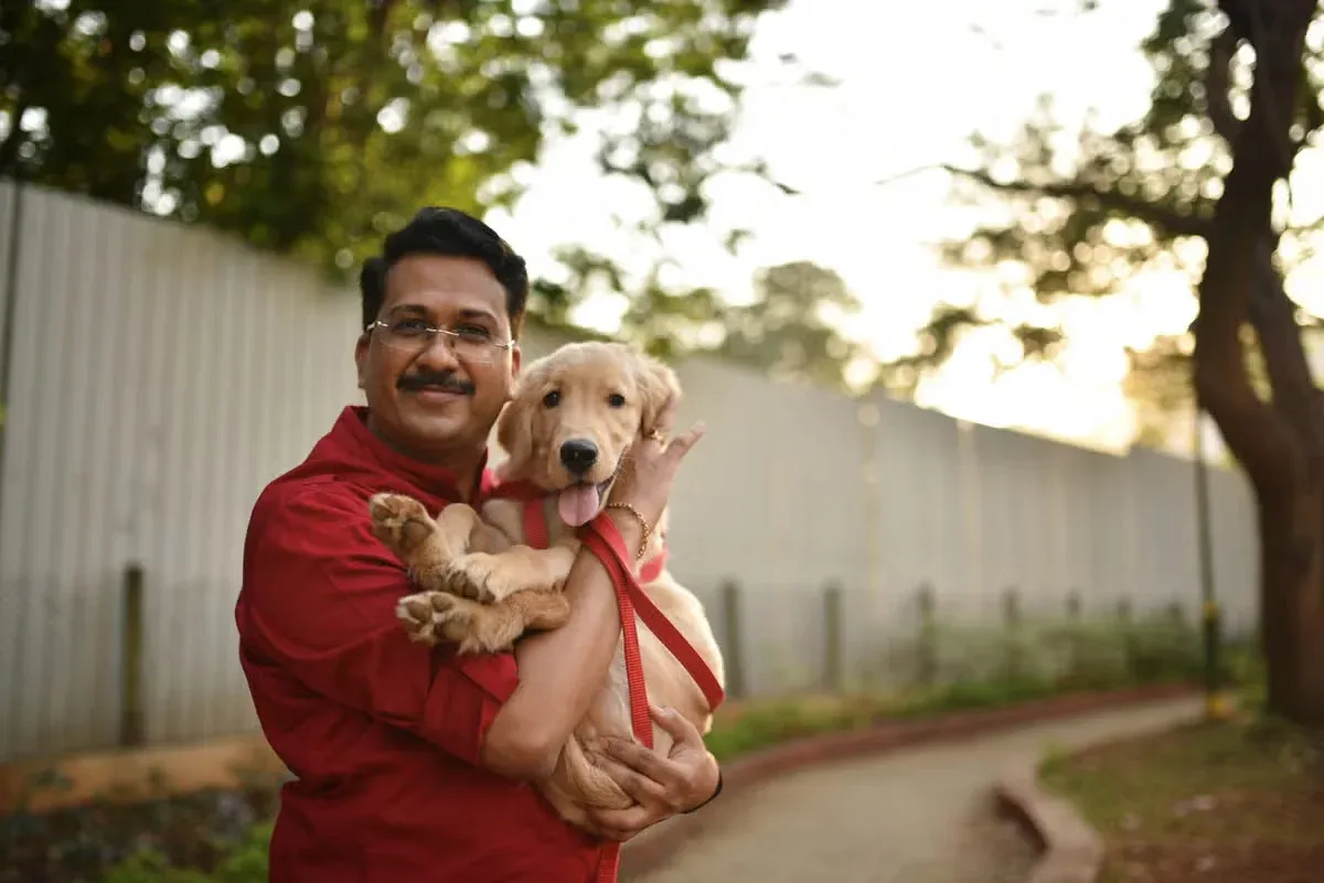 A man cuddling his Labrador retriever puppy who has a Desi dog name.