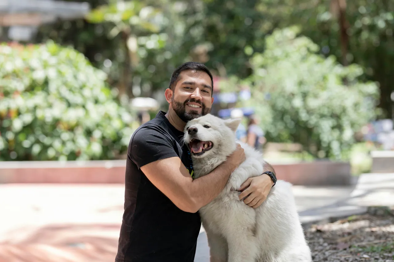 A man hugging his dog at a park in Mexico City.