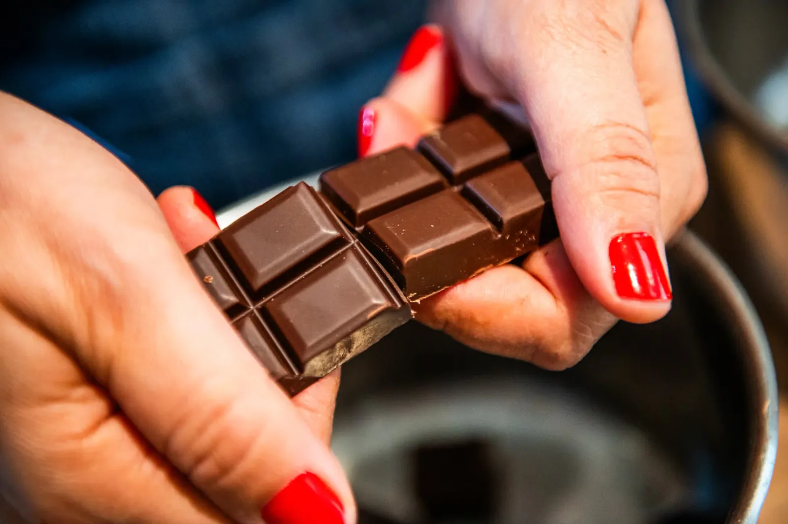 A close-up of someone with squares of chocolate in their hands.