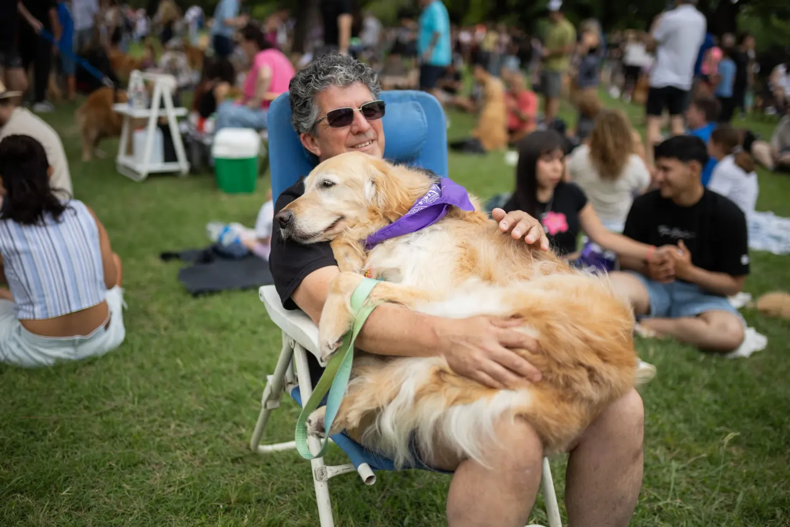 A golden retriever owner sits with his dog on his lap