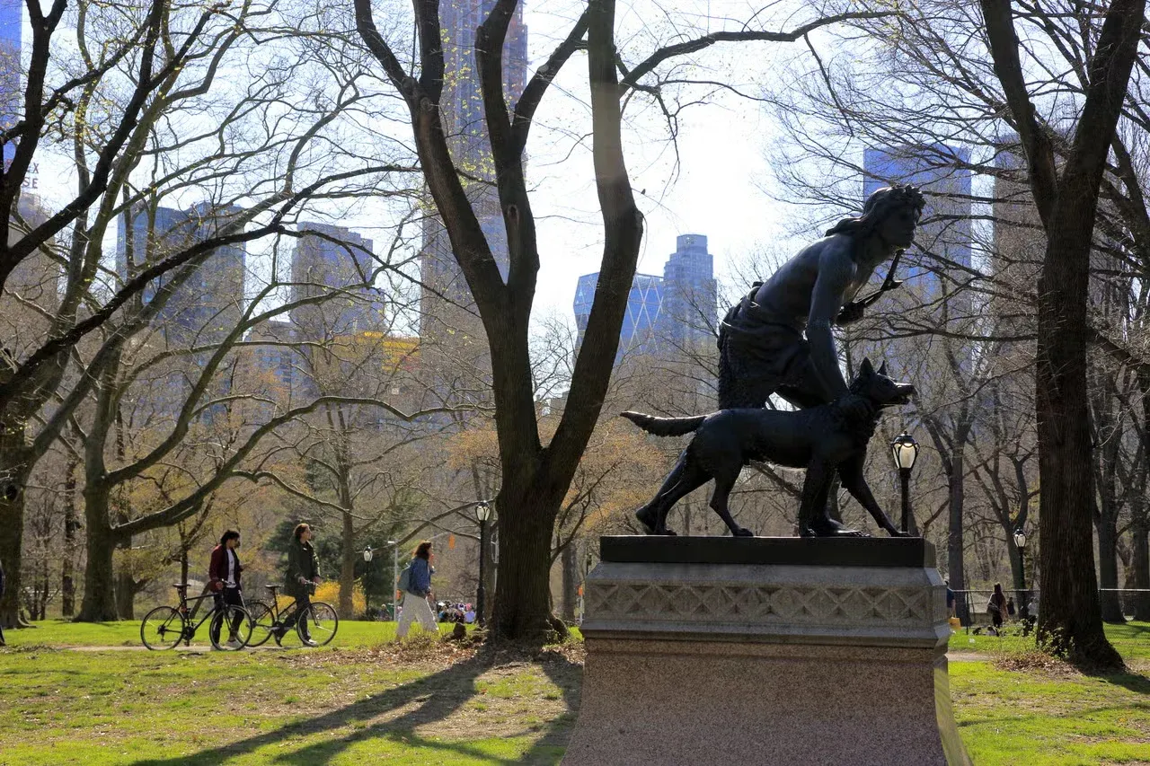 A statue of a Native American man with his dog in Central Park.