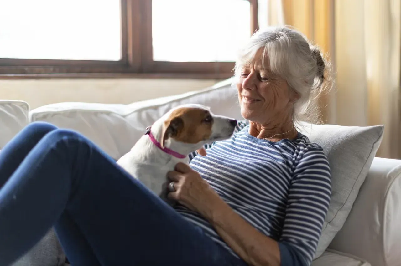 A senior woman cuddling her dog on the couch.